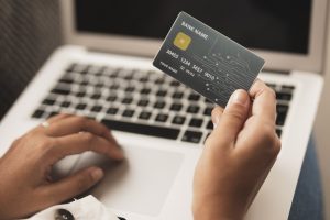 Hand Holding Credit Card Working Laptop 1 Scaled